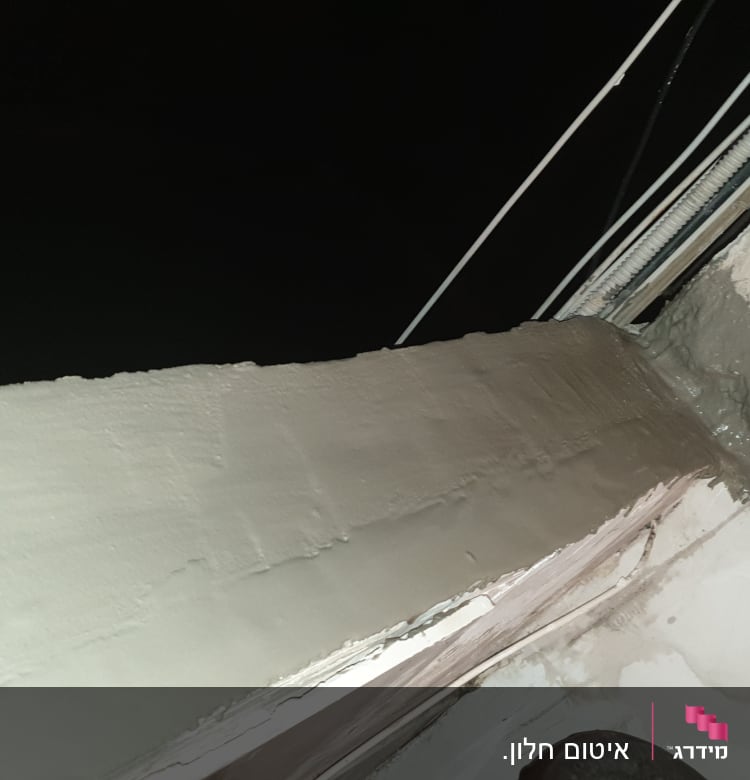 איטום חלון עם חומר אפור על הקיר